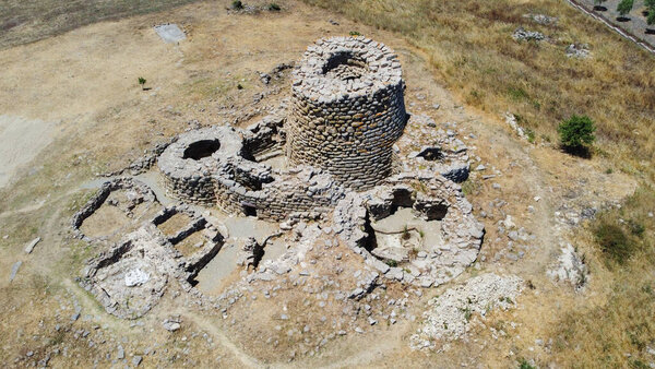 Majestic ruins of nuraghe Piscu in sardinia, italy, stand tall against a vibrant blue sky, showcasing ancient megalithic architecture