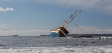 Captivating image of a shipwreck leaning on rocks in a rough sea during sunset, creating a dramatic scene of maritime disaster and the power of nature clipart