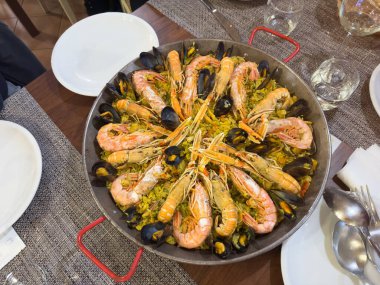 Traditional spanish paella is being prepared with fresh seafood in a pan clipart