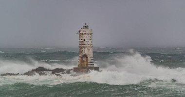 Şiddetli bir fırtına sırasında okyanus dalgaları bir deniz fenerine çarpıyor.