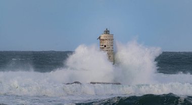 Ocean waves crashing against a lighthouse during a powerful storm at sea clipart