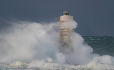 Denizde güçlü bir fırtına sırasında okyanus dalgaları bir fenere çarpıyor.