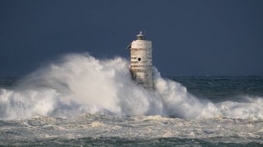 Denizde güçlü bir fırtına sırasında okyanus dalgaları bir fenere çarpıyor.