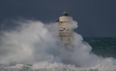 Denizde güçlü bir fırtına sırasında okyanus dalgaları bir fenere çarpıyor.