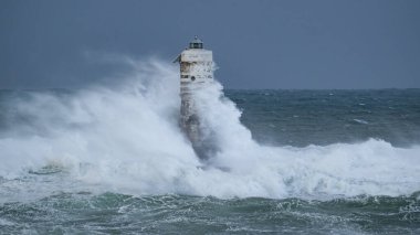 Denizde güçlü bir fırtına sırasında okyanus dalgaları bir fenere çarpıyor.