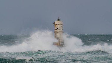 Denizde güçlü bir fırtına sırasında okyanus dalgaları bir fenere çarpıyor.