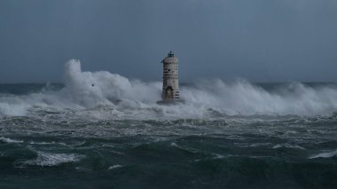 Denizde güçlü bir fırtına sırasında okyanus dalgaları bir fenere çarpıyor.
