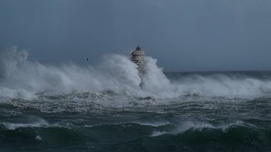 Kasırga sırasında Mangiabarche deniz fenerine çarpan güçlü dalgalar, dayanıklılığı ve doğanın gücünü simgeliyor.