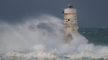 Kasırga sırasında Mangiabarche deniz fenerine çarpan güçlü dalgalar, dayanıklılığı ve doğanın gücünü simgeliyor.