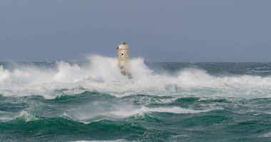 Kasırga sırasında Mangiabarche deniz fenerine çarpan güçlü dalgalar, dayanıklılığı ve doğanın gücünü simgeliyor.