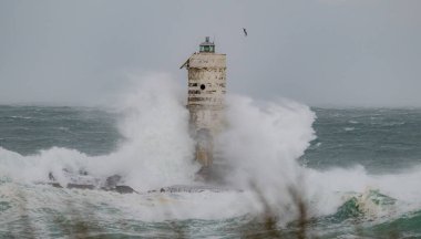 Powerful waves crashing against a Mangiabarche lighthouse during a hurricane, symbolizing resilience and the forces of nature clipart