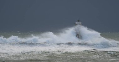 Powerful waves crashing against a Mangiabarche lighthouse during a hurricane, symbolizing resilience and the forces of nature clipart