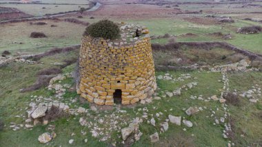 Historic nuraghe tower stands amidst the rugged sardinian landscape, showcasing ancient architecture and cultural heritage clipart