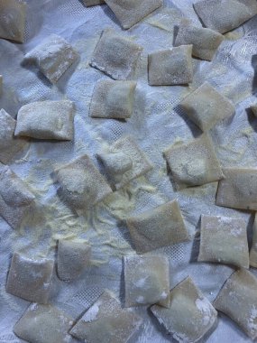 Taze ev yapımı, un tozlu, kumaş üzerinde dinlenen ravioli. Geleneksel İtalyan makarnası, mutfak ve yemek fotoğrafçılığı için mükemmel.