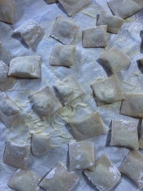 Taze ev yapımı, un tozlu, kumaş üzerinde dinlenen ravioli. Geleneksel İtalyan makarnası, mutfak ve yemek fotoğrafçılığı için mükemmel.