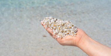 Kristal berrak suda kalp şeklinde kuvars kumu tutan eller.