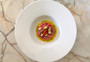 Turşu, ançüez ve aromalı sosla süslenmiş zarif etli tartar.