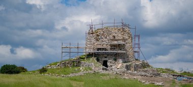 Nuraghe 'nin antik taş kulesi restorasyon sırasında iskelelerle çevrili.