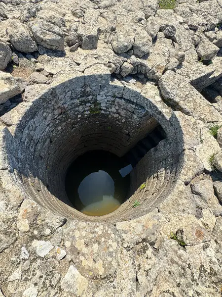 Serri 'deki Santa Vittoria' nın Nuragic Tapınağı 'nın bir parçası olan su dolu antik taş kaplı kutsal kuyu.