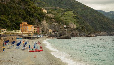 Renkli şemsiyeli, tarihi villalı ve Cinque Terre 'deki yeşil tepeli Monterosso sahili manzarası.