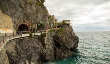 Renkli şemsiyeli, tarihi villalı ve Cinque Terre 'deki yeşil tepeli Monterosso sahili manzarası.