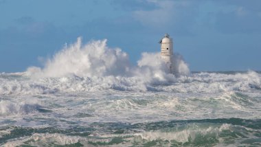 Sert deniz ve güçlü rüzgarlar arasında eski deniz fenerine şiddetli dalgalar çarpar.