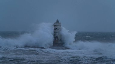 Güçlü okyanus dalgaları ağır deniz fırtınası sırasında ıssız deniz fenerine çarpıyor.