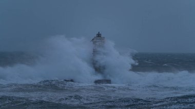 Güçlü okyanus dalgaları ağır deniz fırtınası sırasında ıssız deniz fenerine çarpıyor.