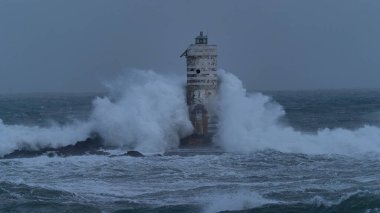 Güçlü okyanus dalgaları ağır deniz fırtınası sırasında ıssız deniz fenerine çarpıyor.