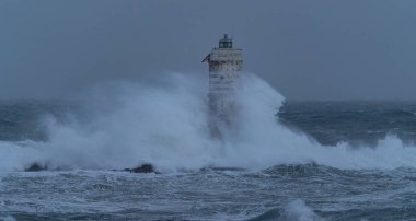 Güçlü okyanus dalgaları ağır deniz fırtınası sırasında ıssız deniz fenerine çarpıyor.