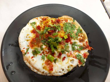 Egg half fry garnish with coriander leaves green onion and spices