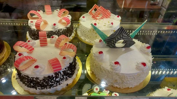 arious Cake with Icing in Refrigerated Bakery Case Cabinet.