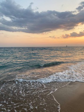 Güneş ışınları ve dalgalarla denizin üzerinde gün batımı.