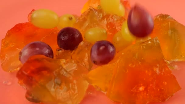 葡萄落在彩色明胶果冻上 粉红的背景 慢动作 — 图库视频影像