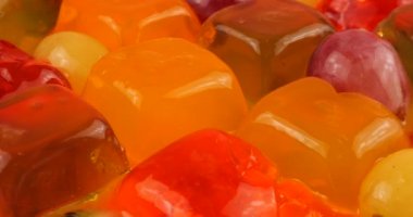 Çok renkli bir böğürtlen jelatin jölesinin üzerine portakal ve kivi dilimleri dökülen üzümler..