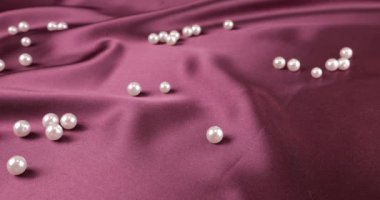 Beyaz kuğu tüyleri menekşe erik ipeğine ve incilere düşer. Yavaş çekim.