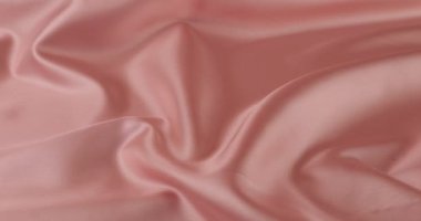 Beyaz kuğu tüyleri pastel pembe ipeğe düşer. Yavaş çekim.