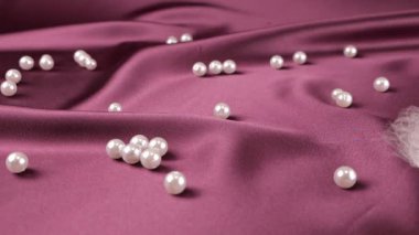 Beyaz kuğu tüyleri menekşe erik ipeğine ve incilere düşer. Yavaş çekim.