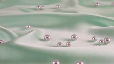 Beyaz kuğu tüyleri soluk mavi ipekten incilere dökülür. Yavaş çekim.