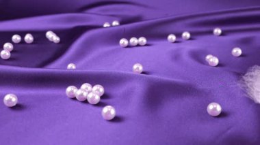 Beyaz kuğu tüyleri mor ipekten inciler üzerine düşer. Yavaş çekim.