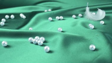 Beyaz kuğu tüyleri incilerle birlikte cyan ipeğine düşer. Yavaş çekim.