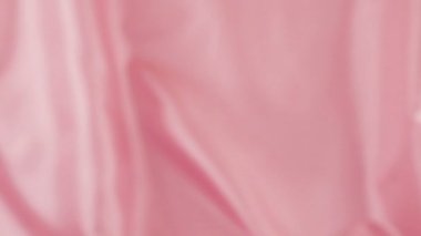 Beyaz kuğu tüyleri ipek renkli pembe arka plana düşer. Yavaş çekim.