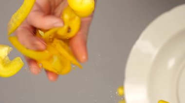 Aşçının ellerinden cam bir yüzeye düşmüş doğranmış tatlı biber dilimleri..