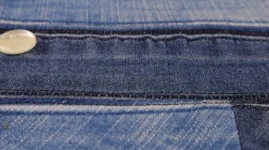 Plastic multi-colored buttons fall on denim. Slow motion.
