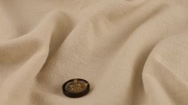 Natural bone color buttons fall on beige natural linen fabric. Slow motion.