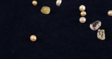 Natural pearls, quartz, rock crystal fall on dark blue velvet. Slow motion.