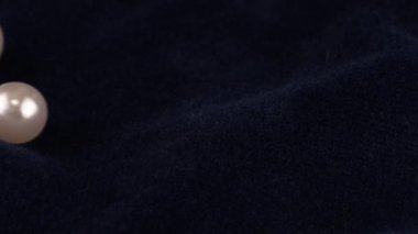 Transparent white jewelry crystals, rock crystal and pearls fall on dark blue velvet.