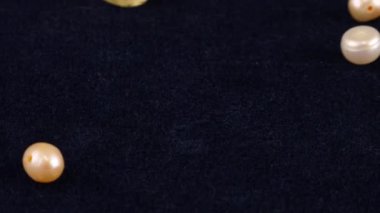 Natural pearls, quartz, rock crystal fall on dark blue velvet. Slow motion.