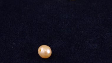 Natural pearls, quartz, rock crystal fall on dark blue velvet. Slow motion.