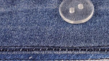 Plastic transparent buttons fall on denim.
